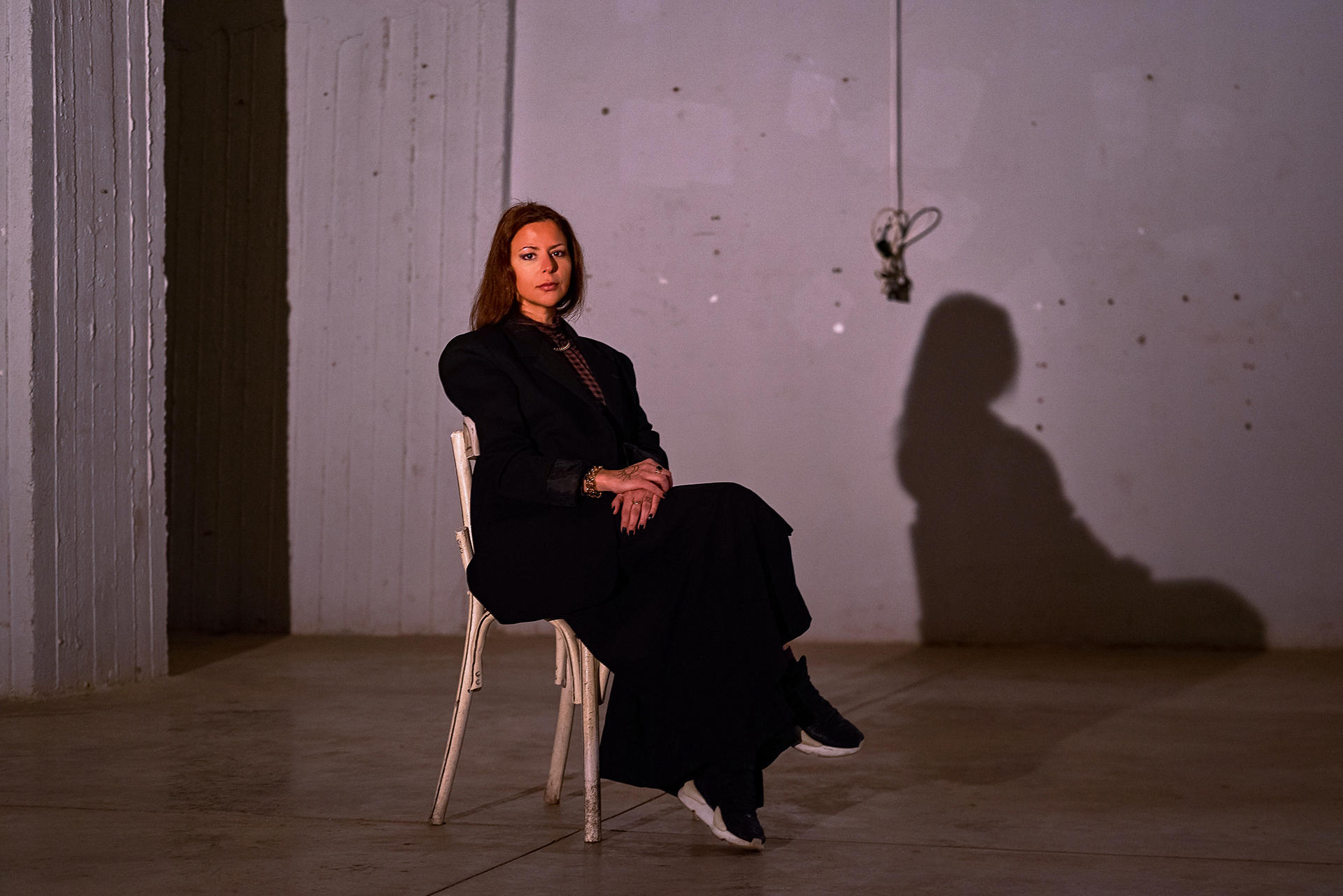 Portrait of Liliane Chlela seated in an industrial space